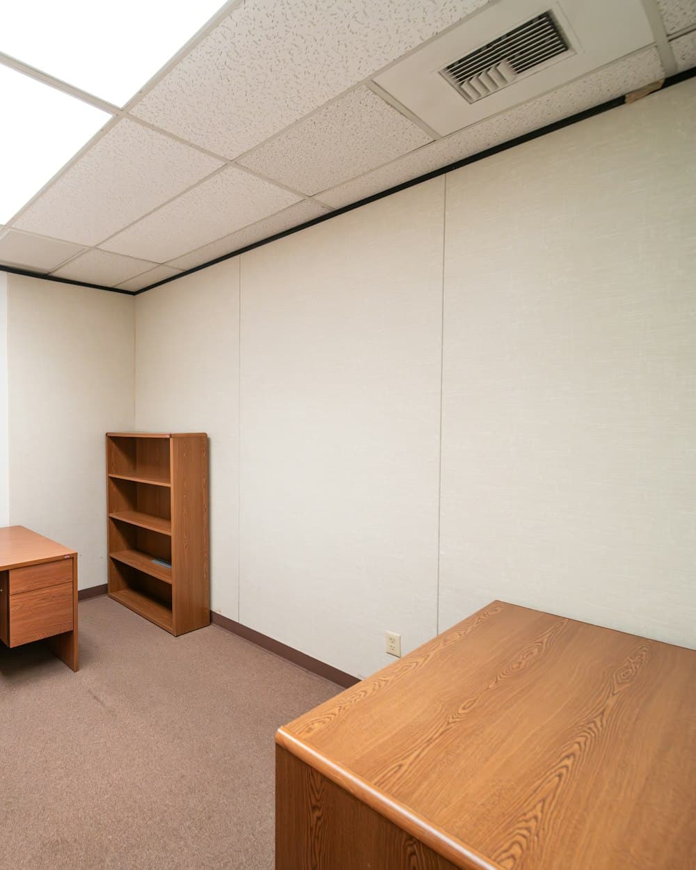 An empty room stripped back before handover, a single wooden shelf unit left against a bare wall.