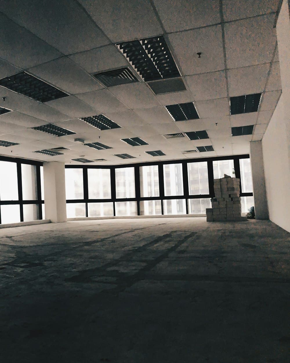 An unoccupied office floor seen from the entrance, a run of windows down one side and nothing on the slab.
