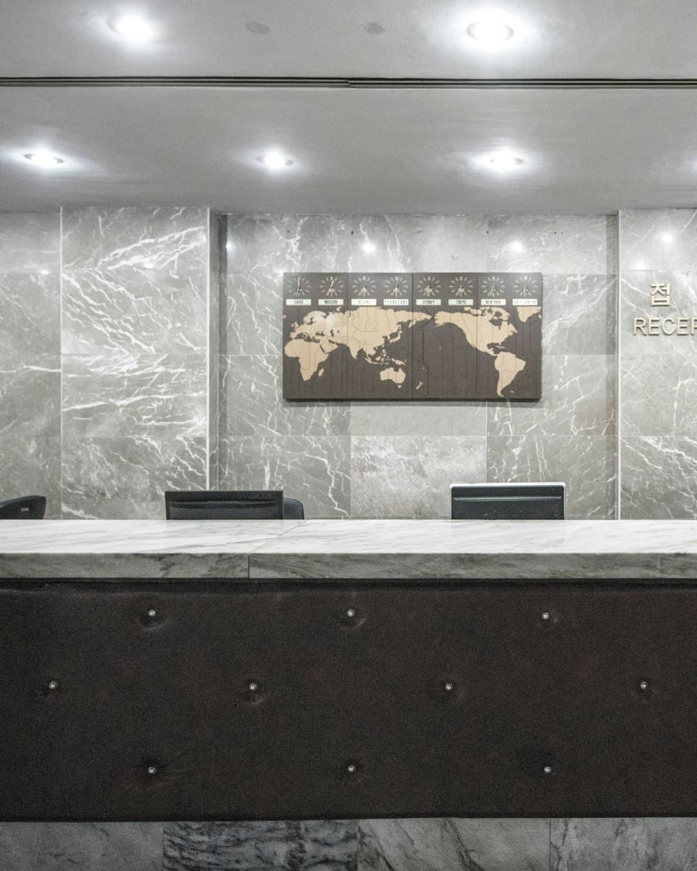 A stone reception counter, clear except for the veined marble wall behind it.